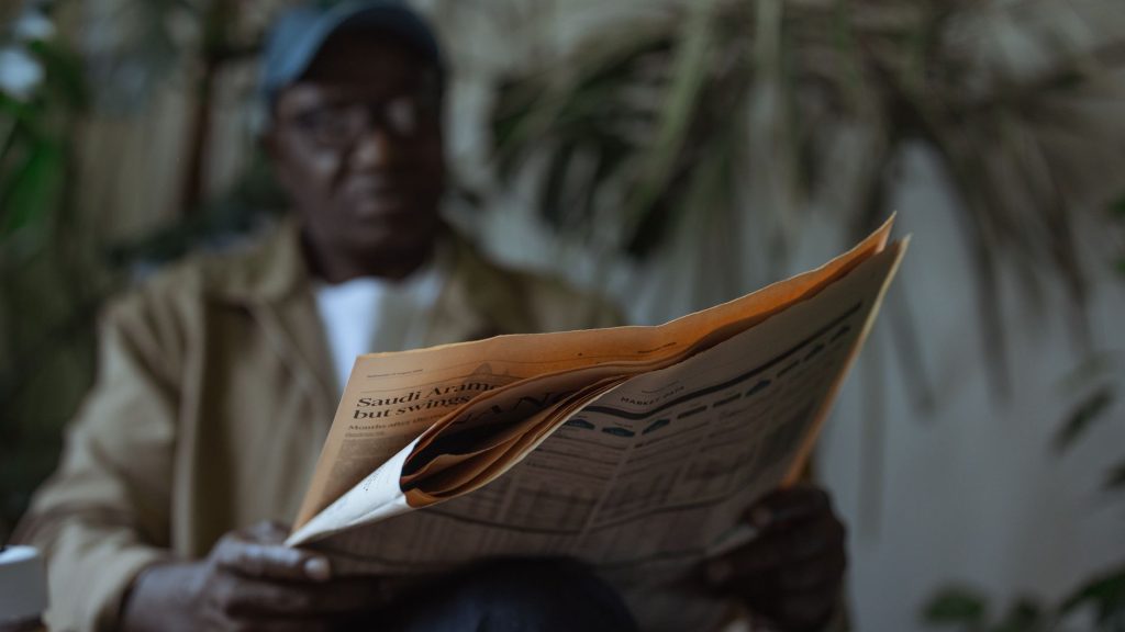 An adult man reading a newspaper indoors, surrounded by plants with a blurred background. — Essential nutrients during medica