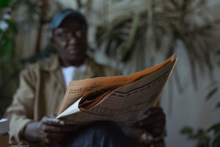 An adult man reading a newspaper indoors, surrounded by plants with a blurred background. — Essential nutrients during medica
