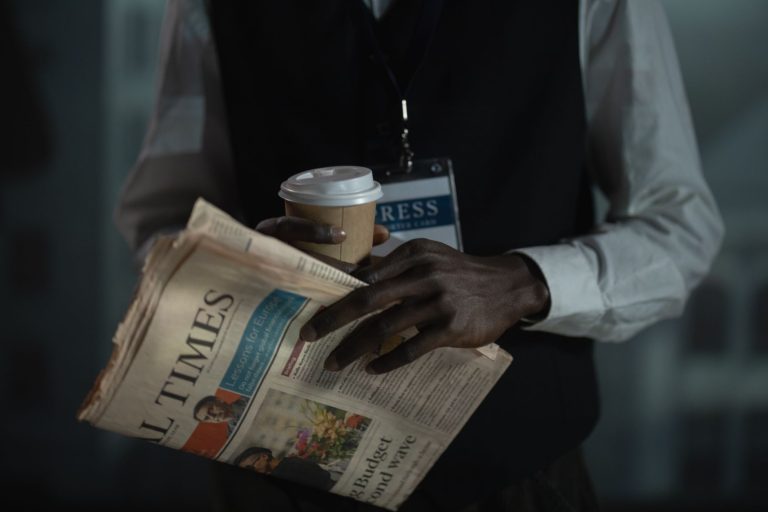 Close-up of a journalist holding a newspaper and coffee cup, conveying press and media concept. — From Chaos to Clarity: The