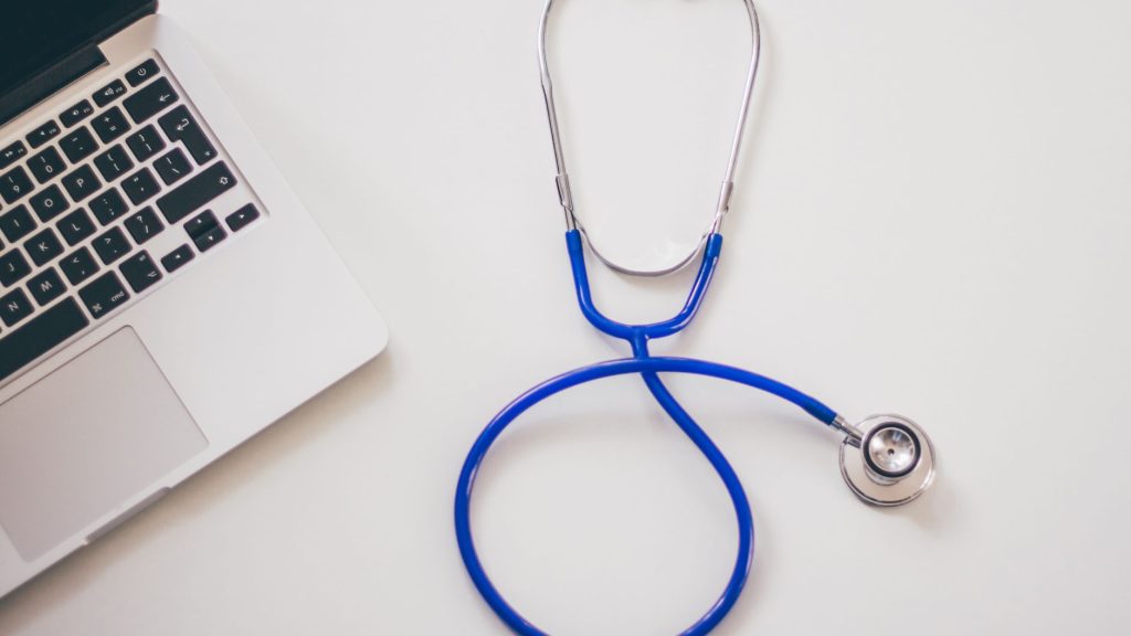 Medical stethoscope and laptop on a white desk, symbolizing digital health solutions. — Understanding the Cost of Facial Fat