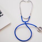 Medical stethoscope and laptop on a white desk, symbolizing digital health solutions. — Understanding the Cost of Facial Fat