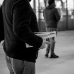 A monochrome image of a person holding newspapers in an urban environment, capturing the essence of street life. — Vavada reg