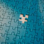 A close-up of a blue jigsaw puzzle with one piece missing, symbolizing the process of piecing together information.