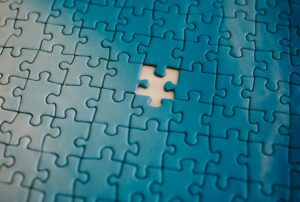 A close-up of a blue jigsaw puzzle with one piece missing, symbolizing the process of piecing together information.