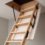 a wooden loft ladder extending from a ceiling hatch in a minimalist home interior